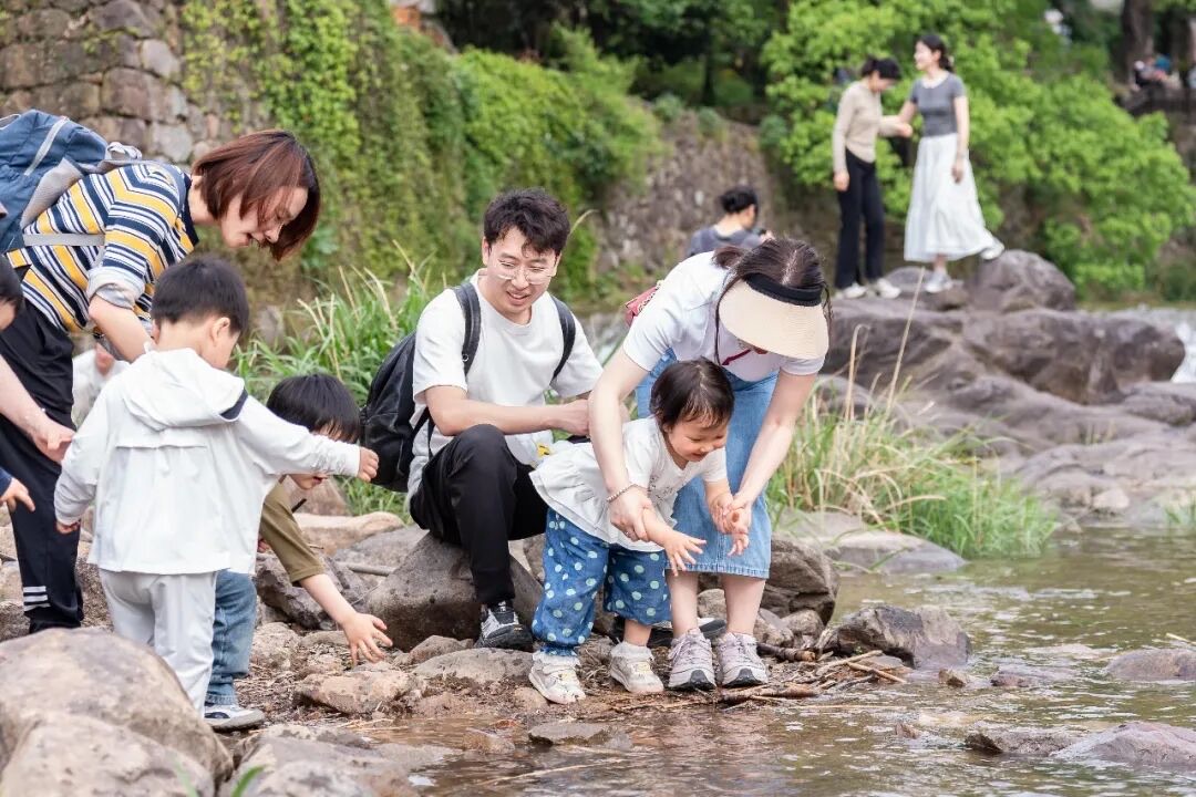 桐庐芦茨湾浅滩溪流，孩子弯腰在石缝里摸螺蛳