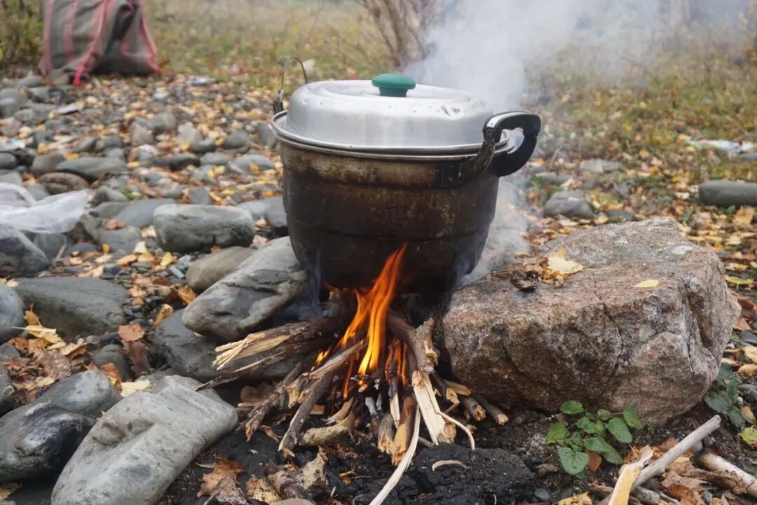 喀纳斯湖畔石滩上柴火现煮奶茶体验场景