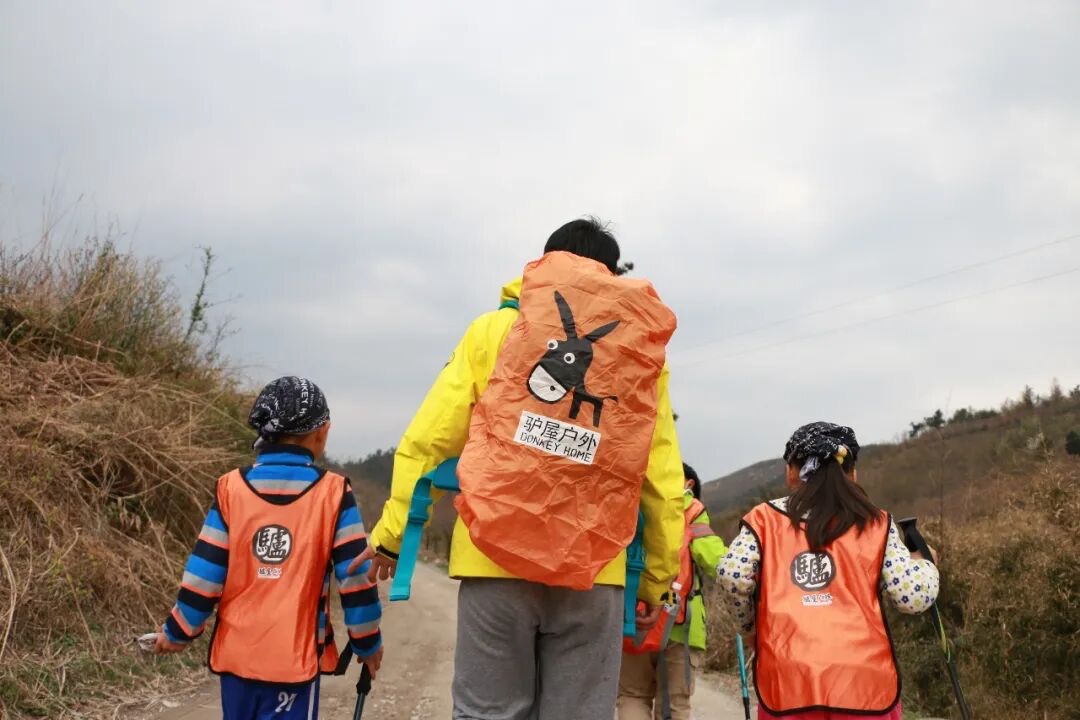 驴屋亲子家庭徒步山野背影，孩子手持登山杖前行
