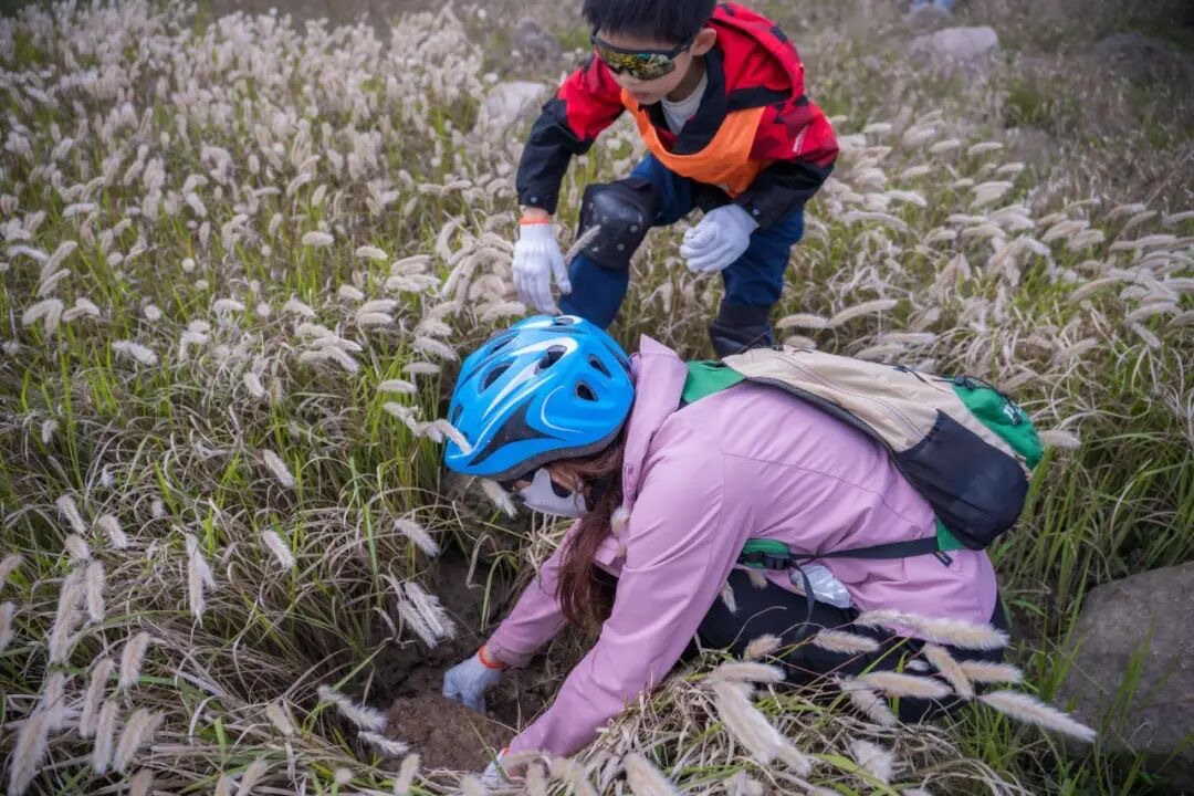 参加骑行营的孩子们戴头盔坐在横沙岛海堤上指向天空