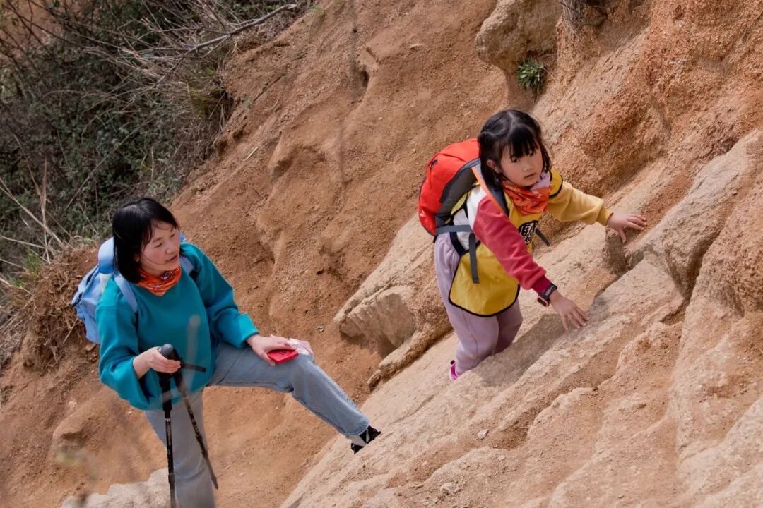 苏州灵白线山脊土坡路段，亲子队员持登山杖向上攀爬