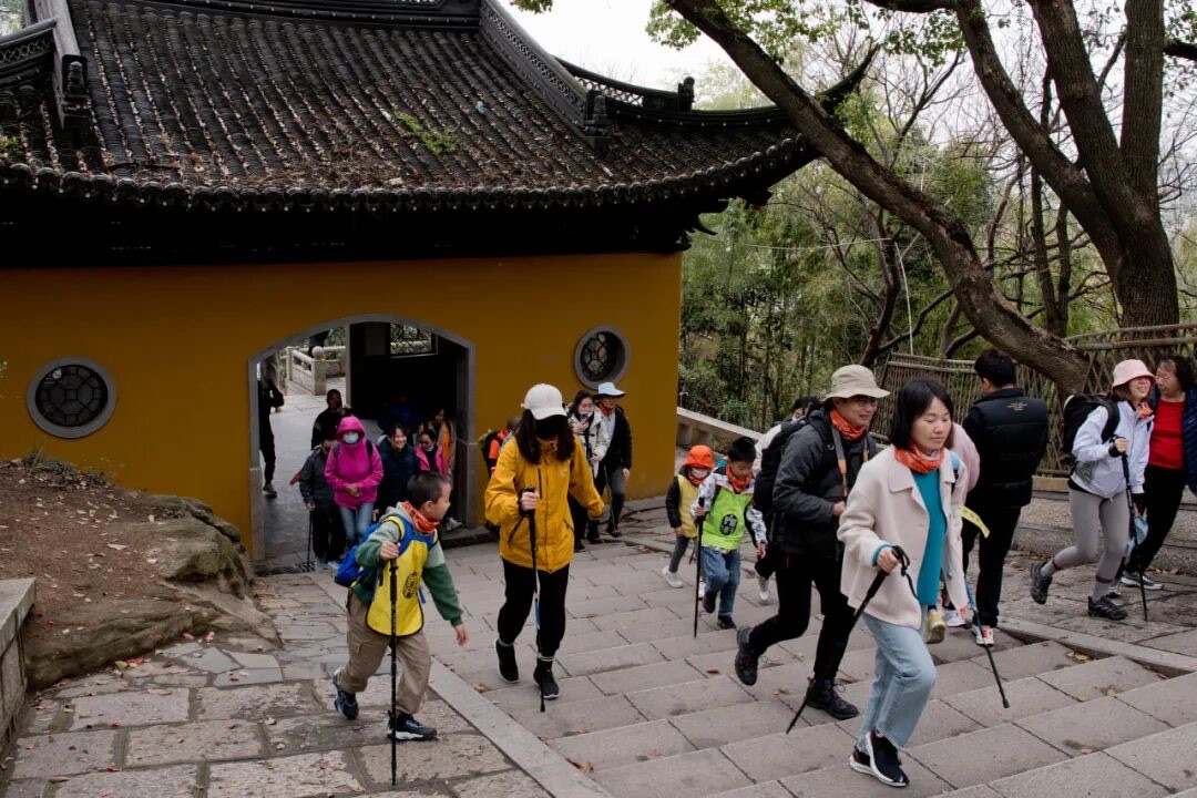 苏州灵白线灵岩山寺路段，亲子队员沿黄色墙垣前的石板台阶上行