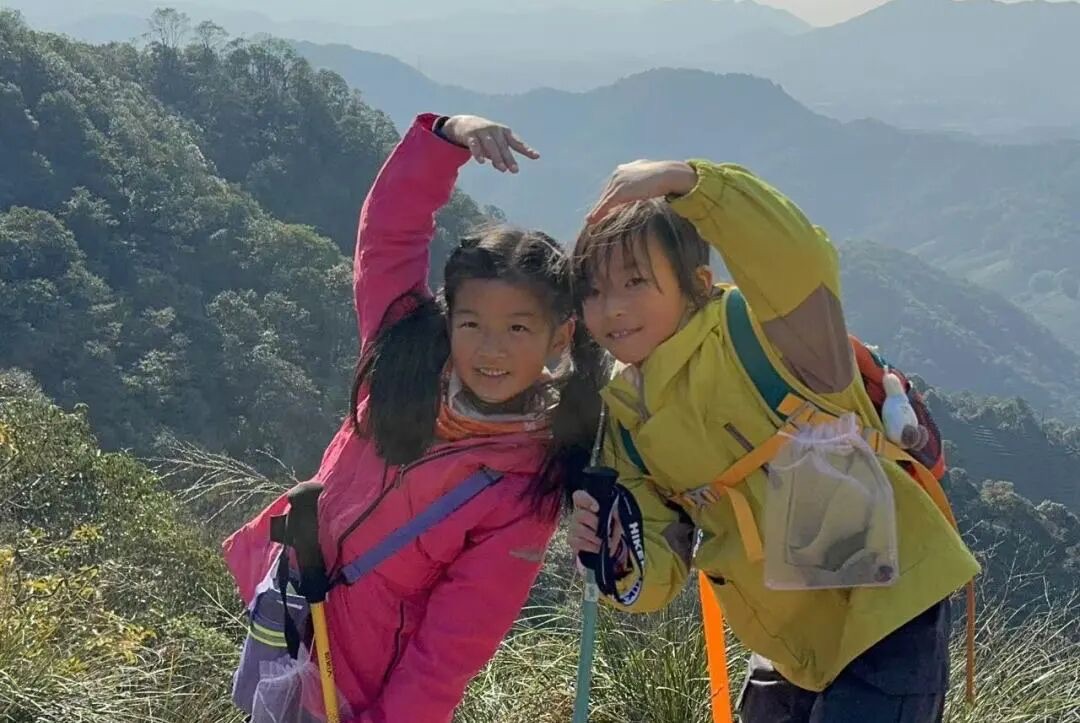 两名背登山包持登山杖的女孩在山脊步道上合影